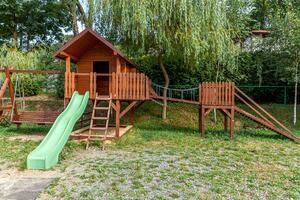 leerer moderner hölzerner kinderspielplatz auf grünem hof im öffentlichen park am sommertag. lustiges Spielzeugland für Kinder. städtische Bewegungsaktivitäten für Kinder im Freien. Kindheitskonzept in der Nachbarschaft. foto