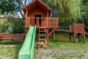 leerer moderner hölzerner kinderspielplatz auf grünem hof im öffentlichen park am sommertag. lustiges Spielzeugland für Kinder. städtische Bewegungsaktivitäten für Kinder im Freien. Kindheitskonzept in der Nachbarschaft. foto