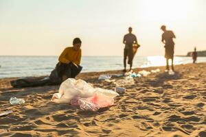 Erde Tag. Freiwillige Aktivisten sammelt Müll Reinigung von Strand Küsten Zone. Frau und mans setzt Plastik Müll im Müll Tasche auf Ozean Ufer. Umwelt Erhaltung Küsten Zone Reinigung. foto