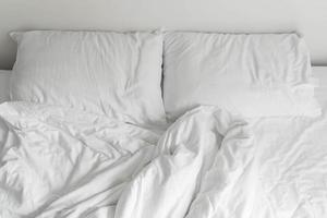 Randbett mit weißer unordentlicher Kissendekoration im Schlafzimmerinnenraum foto