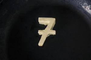Butter in Form von Nummer 7 auf heißer Pfanne - Nahaufnahme Draufsicht foto