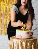 Frau, die ihren Geburtstag feiert, zündet die Kerzen auf der Torte an foto