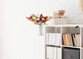Eimer Tulpenblumen neben dem Bücherregal
