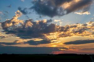 Blauer, violetter, roter Sonnenuntergangshimmelhintergrund mit abendlichen, lockigen, rollenden Wolken kann als Himmelsersatz verwendet werden foto