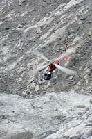 ein Hubschrauber ist fliegend Über ein felsig Berg foto