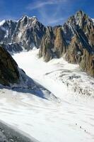 zwei Menschen sind Wandern oben ein Berg mit Schnee bedeckt Berge foto