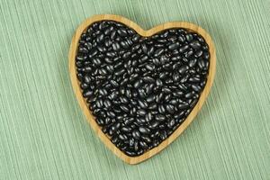 Herz geformt schwarz Bohne Schüssel auf Grün Tischdecke foto
