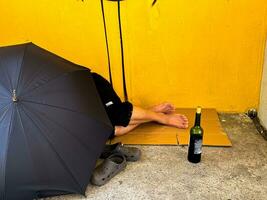 Arm und betrunken Mann Schlafen auf hinter das Regenschirm foto