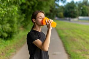 passen Dauer Mädchen Läufer draußen halten Wasser Flasche. foto
