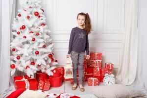 Weiß lange behaart Mädchen dekoriert ein Zimmer mit Weihnachten Spielzeuge. foto