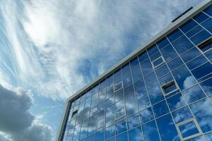 architektonisch Detail von das Fassade mit mehrere Reflexionen von wolkig Himmel und das Sonne. foto