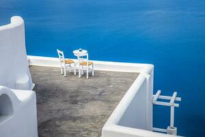 zwei Stühle auf der Terrasse mit Meerblick. insel santorini, griechenland. reise- und urlaubshintergrund. Beste Reiselandschaft für romantische Paare oder Flitterwochen. fantastische Lage und Aussicht foto