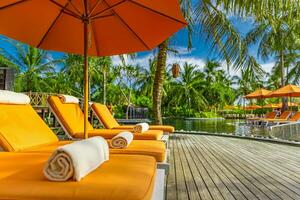 Outdoor-Tourismus-Landschaft. luxuriöses Strandresort mit Swimmingpool und Strandkörben oder Liegen unter Sonnenschirmen mit Palmen und blauem Himmel. Sommerreise- und Urlaubshintergrundkonzept foto