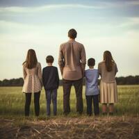 Familie von Papa und vier Kinder Stehen im Feld, suchen in das Entfernung foto