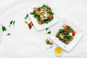 zwei weiße Teller mit Salaten auf weißem Hintergrund foto