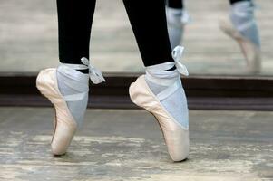 schließen oben Aussicht zu Ballerinas Beine im Punkte auf hölzern Fußboden foto