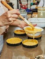 gießen das Teig in klein runden Formen zu machen Kirsche Kuchen foto