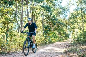 der Mann, der auf einem Bergpfad Fahrrad fährt a foto