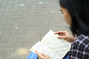 glücklich und Erfolg weiblich asiatisch Hochschule Schüler genießen lesen ein Buch im das Park foto