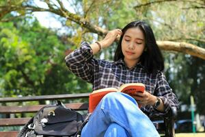 glücklich achtsam jung asiatisch Frau Hochschule Schüler lesen ein Buch im das Park, Bildung Konzept foto