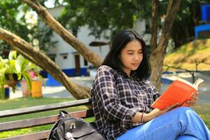 glücklich und Erfolg weiblich asiatisch Hochschule Schüler genießen lesen ein Buch im das Park foto
