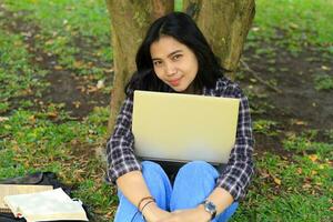 heiter asiatisch Frau Arbeiten Fernbedienung auf Laptop, Video Anruf treffen, und lesen Buch suchen zu Kamera foto