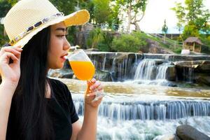 Porträtfrauenhand, die frisch gepressten Orangensaft im Glas hält foto