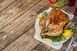 Gebackenes Huhn, Weingläser und Obst zum Abendessen auf dem festlich gedeckten Tisch. Platz kopieren foto