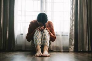 frau sitzt depression dunkelhaarig nachdenklicher blick steht am fenster und angstkopierraum. foto