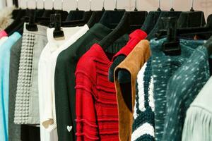 Oberbekleidung auf Kleiderbügeln, Pullover, Röcke, Blusen foto