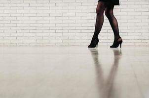 Beine einer Frau in schwarzen Strumpfhosen und hochhackigen Schuhen