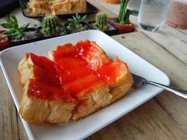 Toast mit Butter und Erdbeermarmelade auf Holzuntergrund foto