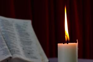 Bibel offen auf einem Tisch mit Kerze foto