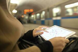 Tablette im weiblich Hände zeigen U-Bahn Karte im unter Tage foto