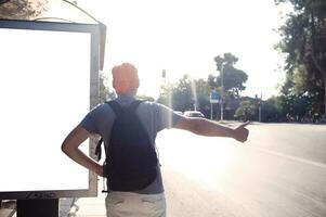 Mann Stehen in der Nähe von Bus halt Daumen ein Aufzug foto