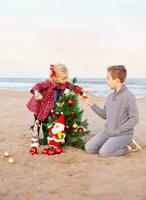 Geschwister vorbereiten zum das Weihnachten Party auf das Strand foto