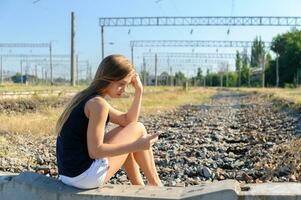 Teenager Mädchen mit Handy, Mobiltelefon Sitzung auf unvollendet Schiene Spur foto