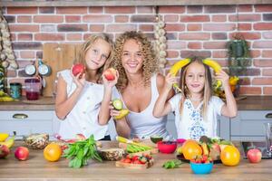 Mutter und Töchter Kochen zusammen im das Küche. gesund Essen Konzept. Porträt von glücklich Familie mit frisch Smoothies. foto