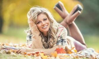 attraktiv jung Frau mit sinnlich Lächeln Lügen im Herbst Park foto