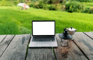 Laptop Computer leer Bildschirm auf ein hölzern Terrasse im das Hintergrund von Reis Felder foto