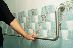 asiatisch Alten Frau verwenden Badezimmer Griff Sicherheit im Toilette, gesund stark medizinisch Konzept. foto