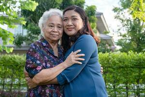 asiatisch Alten Frau Umarmung mit ihr Tochter mit Liebe, Pflege, Hilfe, ermutigen und Empathie beim Park, gesund stark medizinisch Konzept. foto