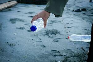 Hand Frau pflücken oben Plastik Flasche Reinigung auf das Strand , Freiwillige Konzept foto