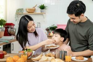 Aktivitäten zusammen während das Feiertage. Eltern und Kinder sind haben ein Mahlzeit zusammen während das Feiertage. mather bereiten Milch zum Sohn auf Morgen, genießen, Wochenende, unbesetzt, Familie Zeit, glücklich. foto