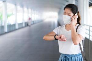 junge Frau mit Maske mit Smartphone während der Pandemie foto