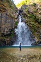 Frau steht vor schönem Wasserfall. foto