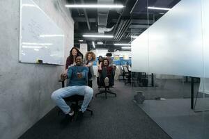 Multiethnisches Geschäftsteam, das auf Bürostühlen rast foto
