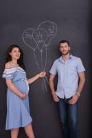 Schwangeres Paar zeichnet seine Fantasie auf Kreidetafel foto