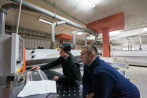 Tischler, die eine CNC-Holzbearbeitungsmaschine berechnen und programmieren foto