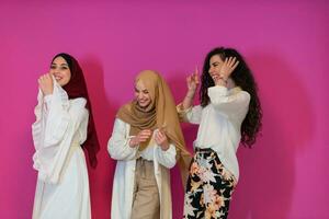 Gruppe Porträt von schön Muslim Frauen zwei von Sie im modisch Kleid mit Hijab isoliert auf Rosa Hintergrund Darstellen modern Islam Mode und Ramadan kareem Konzept foto